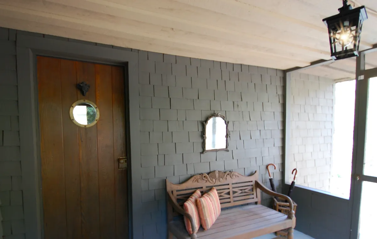 A welcoming entrance scene featuring a wooden door, circular mirror, a sturdy wooden bench, and a hanging lantern. The space is both inviting and imbued with subtle vintage details, suggesting a warm reception and a touch of nostalgia.