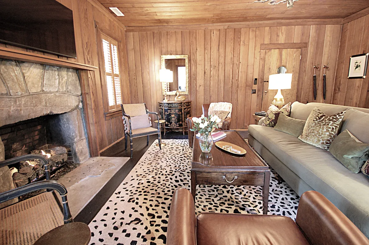 A welcoming living area centered around a stone fireplace, with a plush sofa, coffee table, and a cozy area rug. Warm lighting and comfortable seating create an inviting space ideal for relaxing, socializing, or reading.